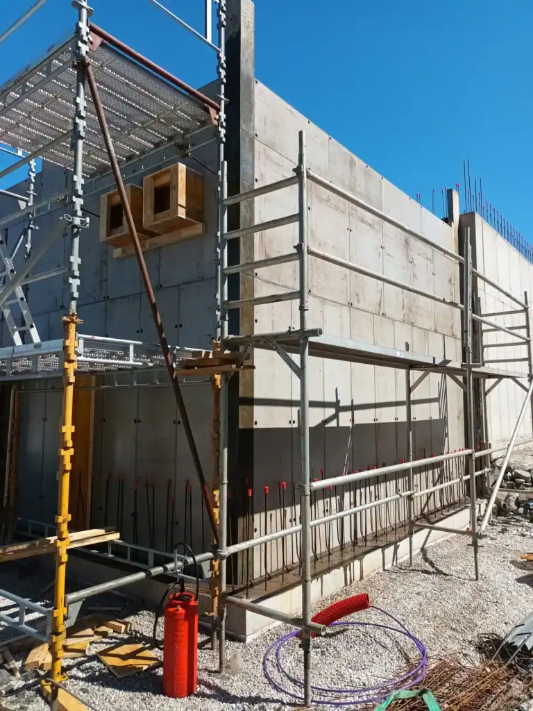 Stabil betongveggkonstruksjon under bygging med sikkerhetsrekkverk og støttestrukturer.