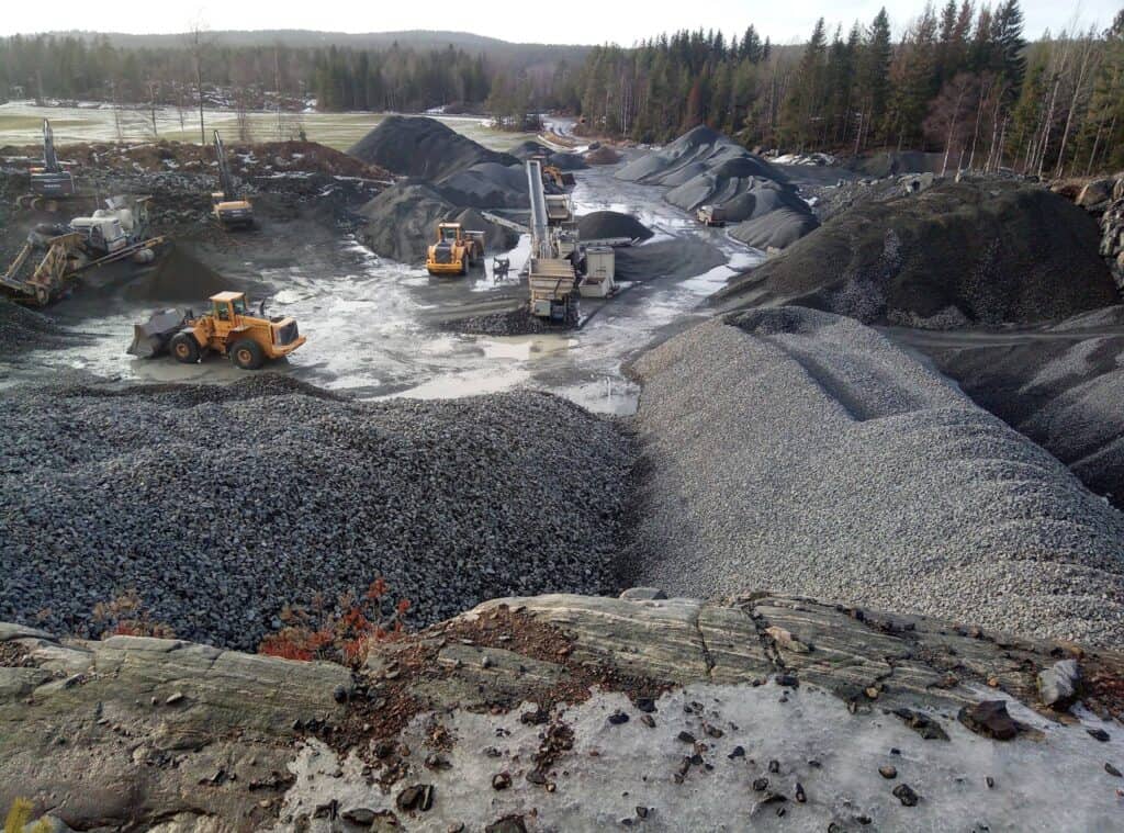 Mølle av grus og pukk med anleggsmaskiner for betongproduksjon, i naturskjønne omgivelser, utendørs anleggsarbeid, tungt maskineri, bygge- og anleggstjenester, R-betong.